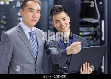 Businessmen talking in computer room Stock Photo