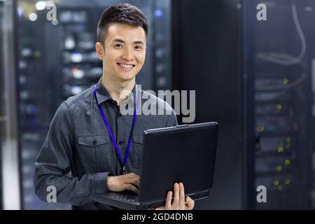 Technician using laptop in computer room Stock Photo