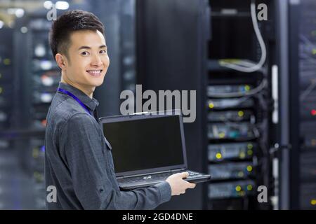 Technician using laptop in computer room Stock Photo