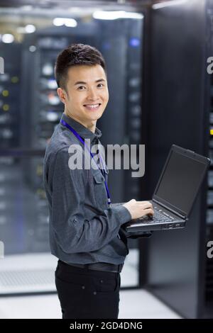 Technician using laptop in computer room Stock Photo