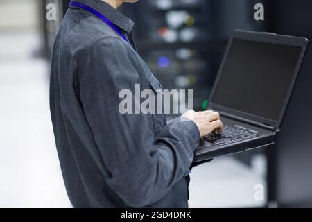 Technician using laptop in computer room Stock Photo