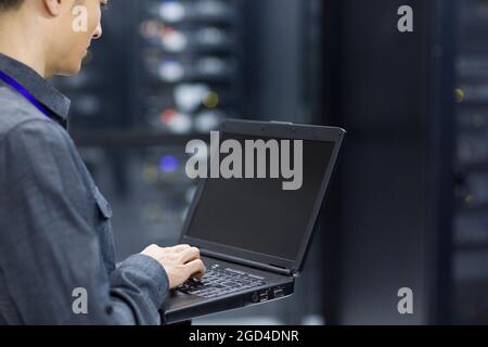 Technician using laptop in computer room Stock Photo