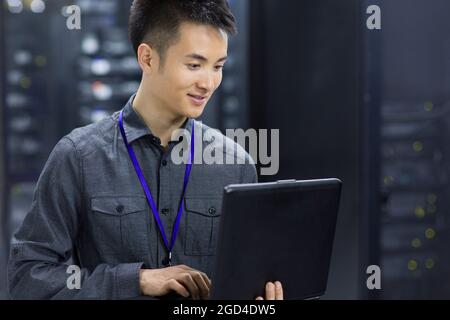 Technician using laptop in computer room Stock Photo