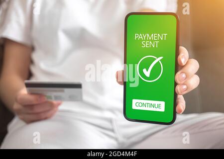Online money transfer confirmed background photo, woman sitting on sofa at home and shopping online Stock Photo