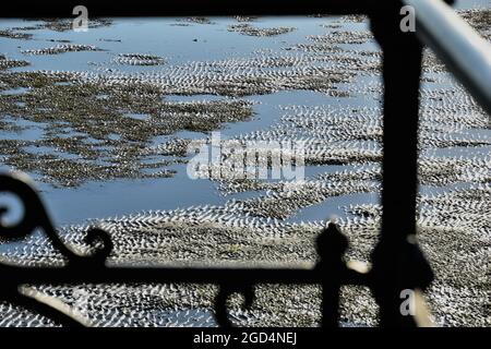 Sandy ripples at low tide Ryde Beach, Isle of Wight through railings on the pier Stock Photo