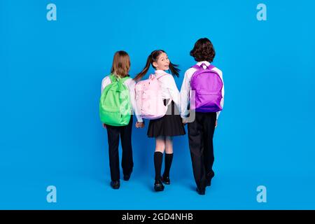 Photo of shiny funny schoolkids formalwear backpacks smiling walking holding arms isolated blue color background Stock Photo