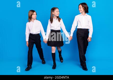 Photo of pretty charming schoolkids formalwear smiling holding arms walking looking isolated blue color background Stock Photo