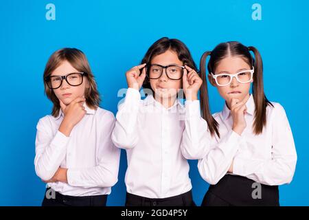 Photo of doubtful unsure schoolchildren wear uniform spectacles arm chin isolated blue color background Stock Photo