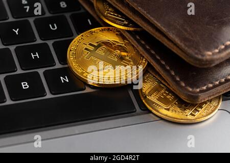 Bitcoin wallet. Wallet with gold coins on the laptop keyboard. Stock Photo
