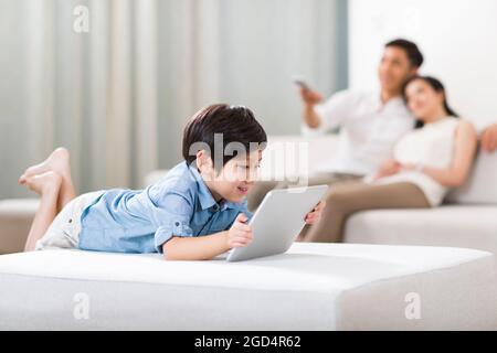 Happy boy playing digital tablet with parents in background Stock Photo