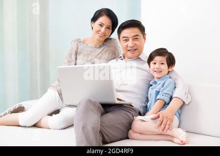 Happy grandparents and grandson with laptop at home Stock Photo