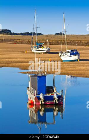 Two fishing boats laying ashore and one anchored in sea water at low tide in Wells-next-the-Sea, England. Stock Photo