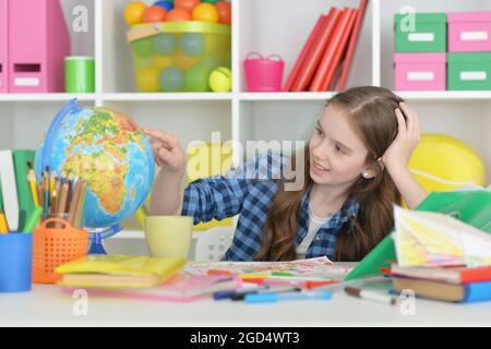 Girl siting at table with globe and studying Stock Photo