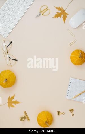 Cozy home office for a blogger or freelancer. Fallen leaves, pumpkins, keyboard, glasses, mouse, notepad and a pen on a beige background. Flat lay. Au Stock Photo