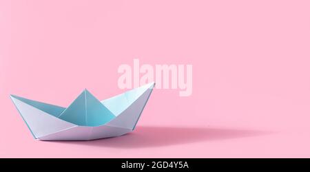 Folded paper origami blue ship with shadow on pink background with copy space Stock Photo