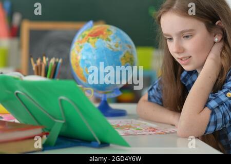 Girl siting at table with globe and studying Stock Photo