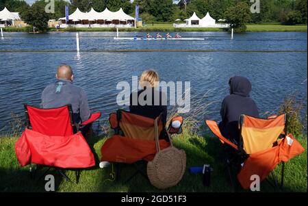 People look on as a crew from Sir William Borlase's Grammar School compete on the opening day of the 2021 Henley Royal Regatta alongside the river Thames. Picture date: Wednesday August 11, 2021. Stock Photo