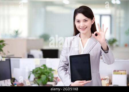 Cheerful office lady with digital tablet doing OK sign Stock Photo