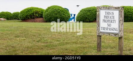 A wooden sign is posted on waterfront private property reading no trespassing in Narragansett Rhode Island. Stock Photo