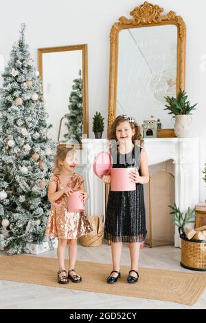 Kids opening Xmas presents. Children under Christmas tree with gift boxes. Decorated living room with traditional fire place. Stock Photo