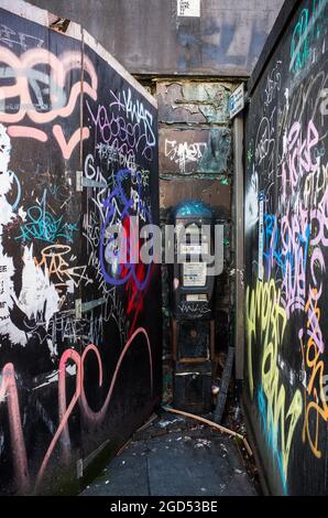 A neglected parking meter in Liverpool city centre surrounded by graffiti and litter. Stock Photo