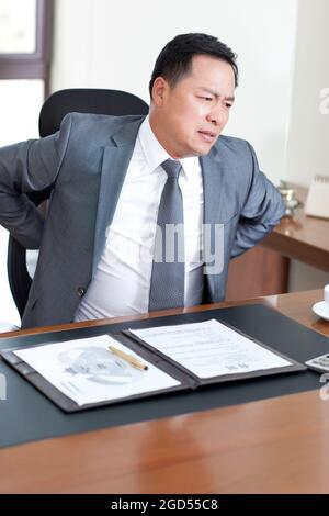 Mature businessman suffering from back pain in office Stock Photo