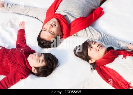 Happy young family lying in snowfield Stock Photo