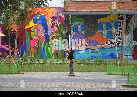 Young girl is roller-skating front of an abandoned building art mural facade at Boulevard Olímpico the grand promenade of Rio de Janeiro in Brazil. Stock Photo