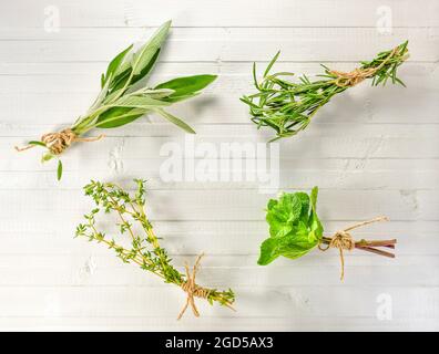 A set of aromatic herbs collected in small bundles of bouquets. Flat lay on a white wooden background. Stock Photo