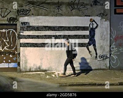Young girl walking on the streets of Santa Teresa with a basket game graffiti in the background in Rio de Janeiro, Brazil. Stock Photo