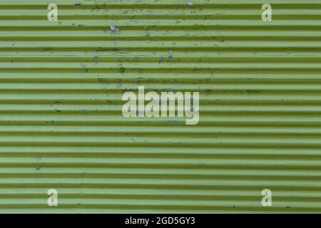 Green rusty corrugated sheet metal with peeling paint and adhesive tape stains. Stock Photo
