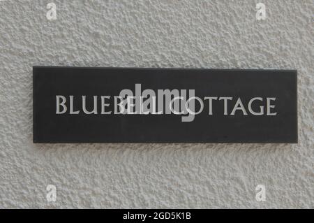'Bluebell Cottage' Sign Engraved on a Welsh Grey Slate Tile and Attached to a White Rendered Wall in Rural Devon, England, UK Stock Photo