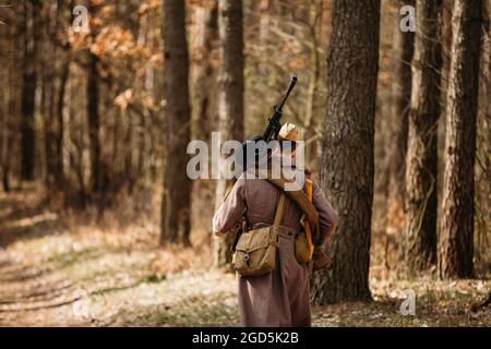 Unidentified re-enactor dressed as Soviet soldier machine gunner goes along a forest road Stock Photo