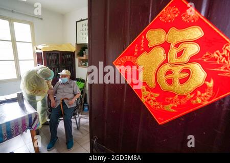 Yangzhou, China's Jiangsu Province. 11th Aug, 2021. A staff member escorts a 93-year-old man home after a COVID-19 nucleic acid testing in Guangling District of Yangzhou, east China's Jiangsu Province, Aug. 11, 2021. The city launched its sixth round of mass nucleic acid testing on Wednesday. Credit: Li Bo/Xinhua/Alamy Live News Stock Photo