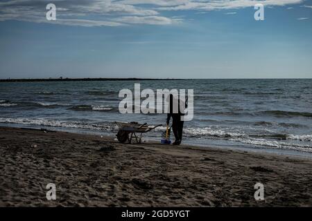 Makassar, South Sulawesi, Indonesia. 11th Aug, 2021. A janitor cleans up trash on a beach in Makassar City, South Sulawesi, Indonesia. Even though it is still in the pandemic period, the cleanliness of the beach is still maintained so that it remains clean and beautiful for the public to visit. (Credit Image: © Herwin Bahar/ZUMA Press Wire) Stock Photo