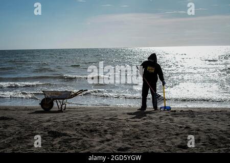 Makassar, South Sulawesi, Indonesia. 11th Aug, 2021. A janitor cleans up trash on a beach in Makassar City, South Sulawesi, Indonesia. Even though it is still in the pandemic period, the cleanliness of the beach is still maintained so that it remains clean and beautiful for the public to visit. (Credit Image: © Herwin Bahar/ZUMA Press Wire) Stock Photo