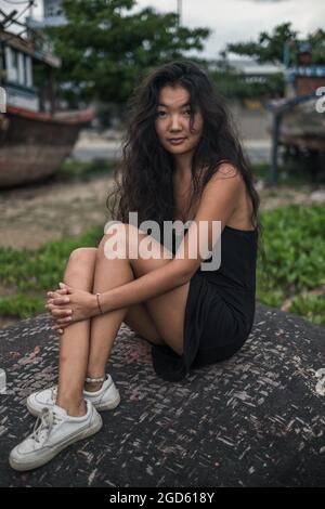 holding her legs. Black long curly hair. Looking at camera with copy space. . High quality photo Stock Photo