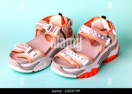 Women's, fashionable, sports sandals with orange accents on a blue background. New youth shoes for girls. Front view. Stock Photo