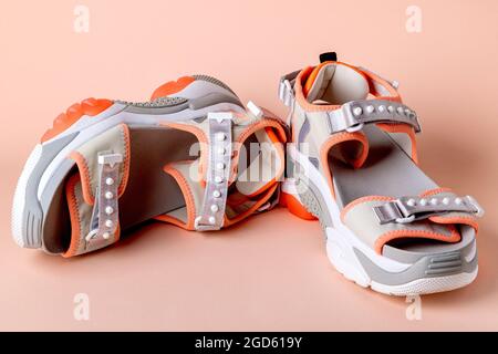 Women's, fashionable, sports sandals with orange accents on a pink background. New youth shoes for girls. Front view. Stock Photo