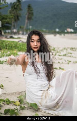 Wearing white dress. Looking at camera with copy space. Brunette long curly hair. Romantic photo. High quality photo Stock Photo