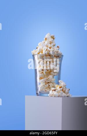 crystal glass with popcorn on a white box and a blue background; no people Stock Photo