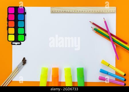 Back to school. Education concept. Drawing. Paints, markers, felt tip pens, colored pencils, ruler with white sheet for text on orange background. Cop Stock Photo