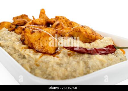 Chicken with aubergine puree, on white plate, on white background, eggplant pure, roasted eggplant Stock Photo