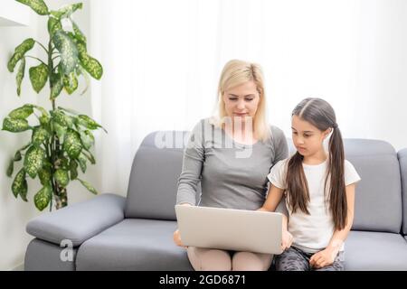 Helpful mother explaining to daughter about using a laptop Stock Photo