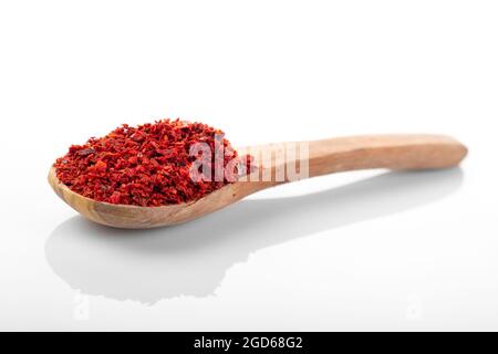 Chili pepper flakes. Chili pepper flakes in wooden spoon, on white background. macro shot chili pepper. Stock Photo