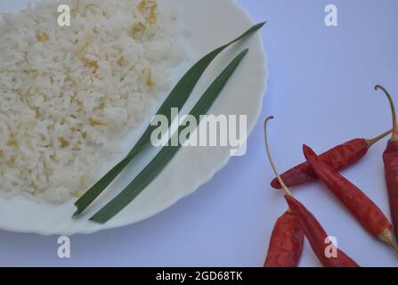 Closeup shot of rice in white plate with red chilli peppers isolated over white background Stock Photo