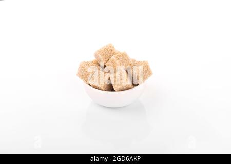 brown sugar cubes. brown sugar in white bowl on white background. sugar cubes, cane sugar. macro shot sugar Stock Photo