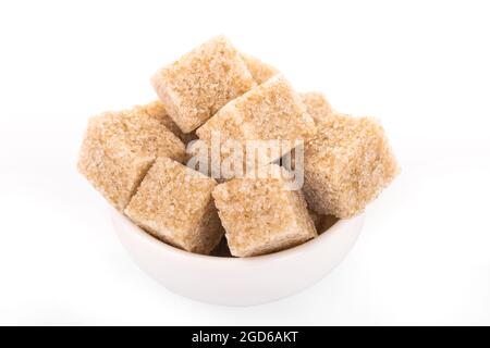 brown sugar cubes. brown sugar in white bowl on white background. sugar cubes, cane sugar. macro shot sugar Stock Photo