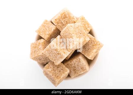 brown sugar cubes. brown sugar in white bowl on white background. sugar cubes, cane sugar. macro shot sugar Stock Photo