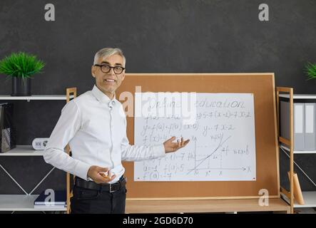 Portrait of math teacher standing in front of classroom board during online class Stock Photo